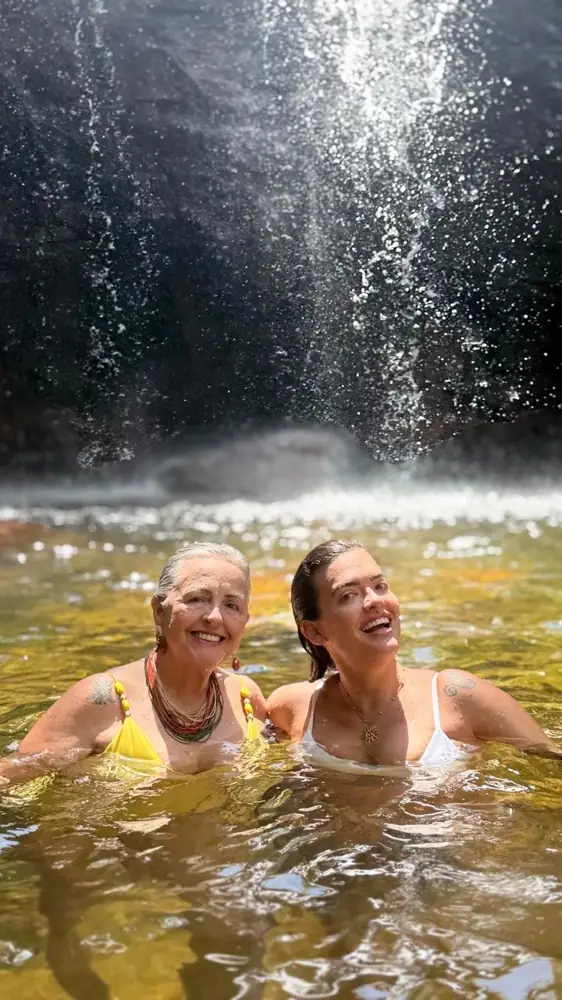Duas clientes sorrindo na água de uma cachoeira